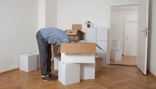 homme penché en avant la tête dans cartons de déménagement